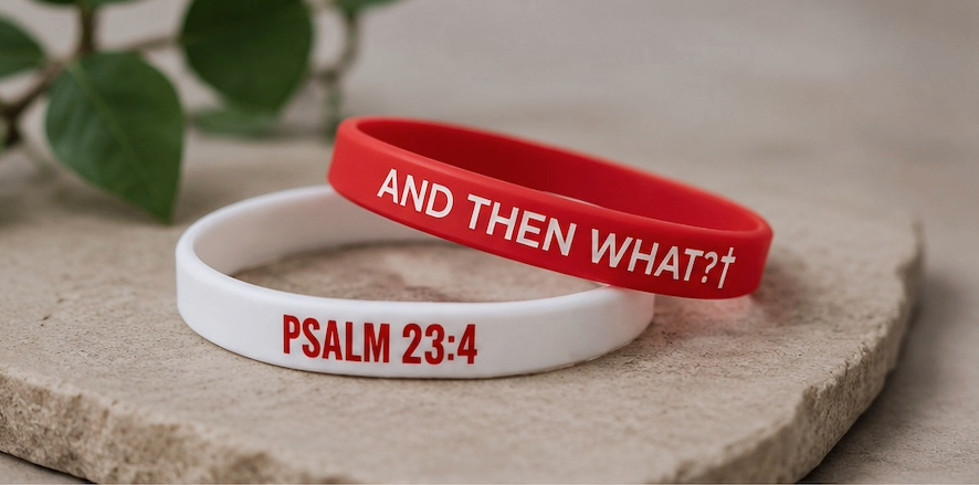 Two wristbands, one red and one white, with text on a stone surface.